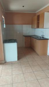 Royal Gidlas Guesthouse في Saulspoort: مطبخ فارغ مع ثلاجة بيضاء ودواليب