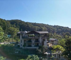 a house on top of a hill with trees at Saraiville- A Boutique Riverside Resort in Dehradun