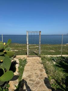 un cancello sulla spiaggia con l'oceano sullo sfondo di CasAmare a Pizzolungo