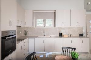 a kitchen with white cabinets and a glass table at Loft Nikando in Tsilivi