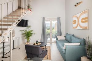 a living room with a blue couch and a staircase at Loft Nikando in Tsilivi