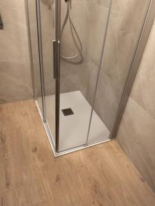 een douche met een glazen deur en een houten vloer bij Casa Nelly by Ca-Sa Check in Andalo +26 foto's