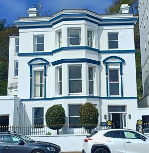 Kings' House في دوغلاس: بيت ابيض فيه سيارات تقف امامه