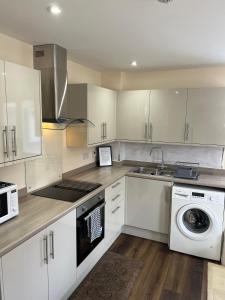 a kitchen with white cabinets and a sink and a dishwasher at Canal View Cottage in Winchburgh