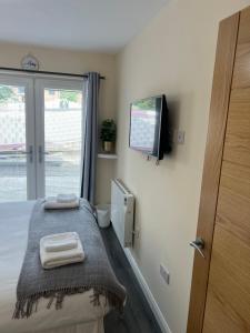 a bedroom with a bed with a tv on the wall at Canal View Cottage in Winchburgh