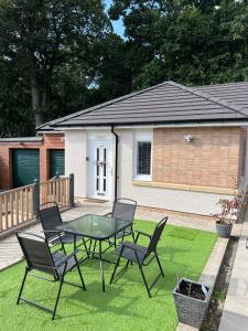 a patio with a table and chairs on the grass at Canal View Cottage in Winchburgh