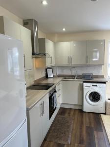 a kitchen with white cabinets and a sink and a dishwasher at Canal View Cottage in Winchburgh +21 photos