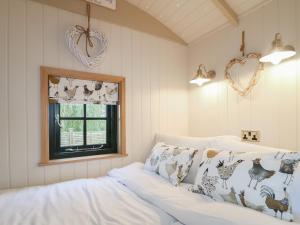a bedroom with two white beds and a window at Poppie's Shepherd Hut - Uk50227 in Redmile