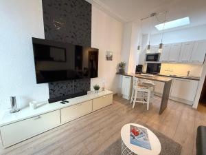 a living room with a large television and a kitchen at Haus Solymar, Whg 44 in Grömitz