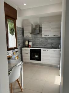 een keuken met witte kasten, een tafel en een fornuis bij MIRO'S Casa Vacanze Pompei in Pompei