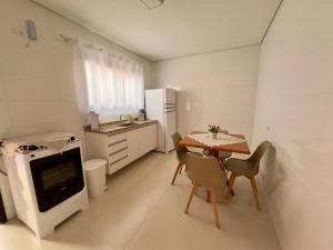 a small white kitchen with a table and chairs at Vila dos Pinheiros 3 in Serra Negra