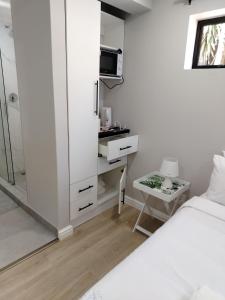 a white bedroom with a bed and a desk with a microwave at Cosmic View Lodge in East London