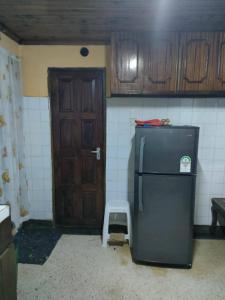 Zack's Serene House في Kisii: مطبخ مع ثلاجة وباب خشبي