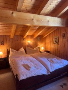 a large bed in a room with wooden walls at Chalet Famicha by Jolidi in Nendaz