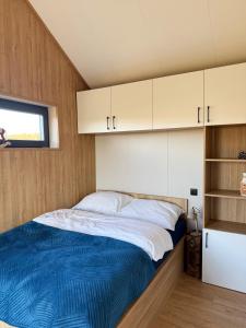 - un lit dans une petite chambre avec des armoires blanches dans l'établissement Leśna Balia - Domek z balią na wyłączność, à Stogniewice