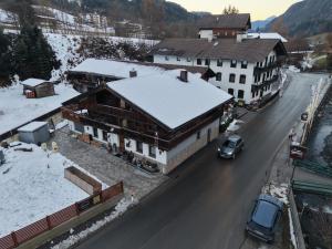 a building with snow on the roof next to a road at Feriendomizil Garber-Bründl in Oberau +6 photos