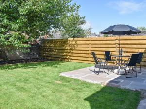 a table and chairs with an umbrella in a backyard at Beckside House in Dalton in Furness