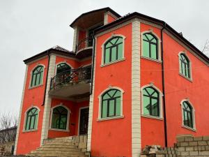a red building with a balcony on top of it at Quba Şah Villa in Amsar