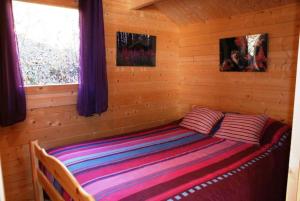 een bed in een blokhut met een raam bij Chalets Sybelles in Saint-Sorlin-dʼArves