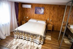 a bedroom with a large bed in a room with wooden walls at FLH - Trofeul Cerbului in Negrileşti