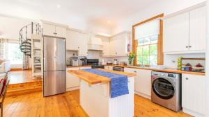 een keuken met witte kasten en een wasmachine en droger bij Waymaker Cottage in Franschhoek