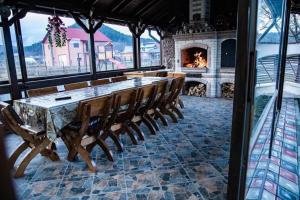 a dining room with a long table and a fireplace at FLH - Trofeul Cerbului in Negrileşti