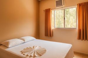a bedroom with a white bed with a window at Hotel Benfica in Aparecida