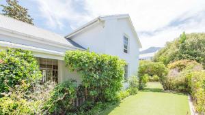 een wit huis met een tuin ervoor bij Waymaker Cottage in Franschhoek