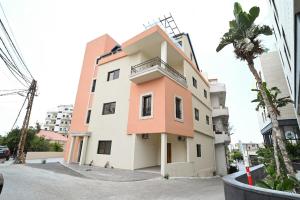 a building on a street with a palm tree at Sands Guesthouse Apartment 03 In Batroun in Batroûn