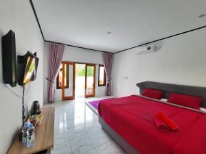 a bedroom with a red bed and a television at Dua Bidadari Villa in Cikanteh