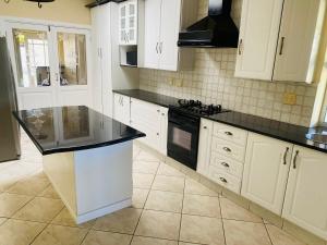 a kitchen with white cabinets and a black counter top at PJ Guest House in Gqeberha