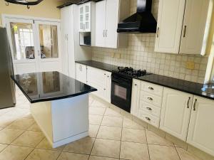 a kitchen with white cabinets and black counter tops at PJ Guest House in Gqeberha +30 photos