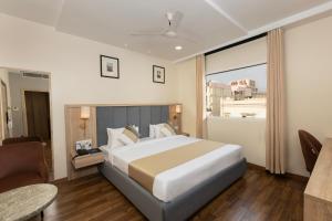 a bedroom with a large bed and a large window at asar Capoors Hotel by Orion Hotels in Lucknow