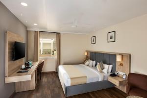a hotel room with a bed and a television at asar Capoors Hotel Hazratganj by Orion Hotels in Lucknow
