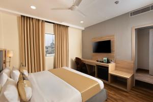 a hotel room with a bed and a desk and a television at asar Capoors Hotel by Orion Hotels in Lucknow