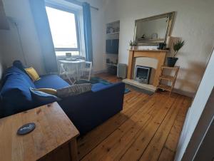 a living room with a blue couch and a fireplace at Cosy 1 bedroom flat close to city centre in Edinburgh