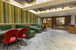 a restaurant with green and red chairs and tables at asar Capoors Hotel Hazratganj by Orion Hotels in Lucknow
