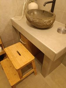een stenen kom op een aanrecht met een houten krukje bij Rooster Retreat in Aridaía