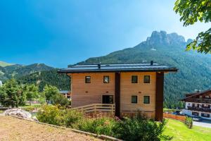 una gran casa de madera con montañas en el fondo en Noah Suites, en Vigo di Fassa