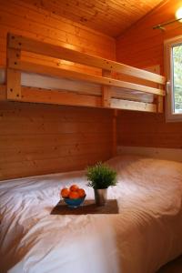 ein Bett in einer Blockhütte mit einer Schale Orangen in der Unterkunft Les Gites De Chauzon 3 Avec Piscine in Chauzon