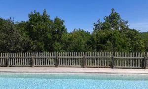 ein Holzzaun mit einem Pool davor in der Unterkunft Les Gites De Chauzon 3 Avec Piscine in Chauzon + 2 Fotos