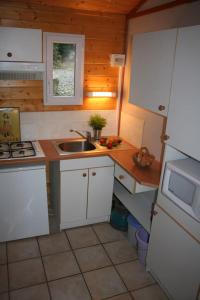 eine kleine Küche mit weißen Schränken und einer Spüle in der Unterkunft Les Gites De Chauzon 3 Avec Piscine in Chauzon