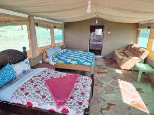 a bedroom with a bed and a couch in a room at Oloiba Nkuti Lodge in Masai Mara