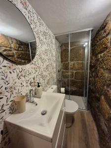 een badkamer met een wastafel, een toilet en een spiegel bij Casa das Pédrinhas Pousade Guarda in Guarda