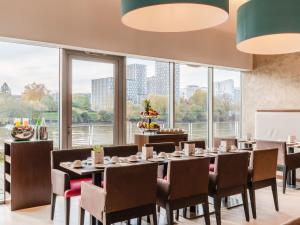 a dining room with tables and chairs and large windows at Residhome Nantes Berges De La Loire in Nantes