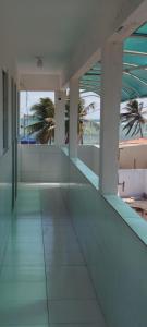 un couloir d'un bâtiment avec des palmiers en arrière-plan dans l'établissement Pousada Rio Mar, à Maxaranguape 11 autres photos