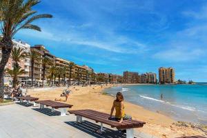 Eine Frau auf einer Bank am Strand in der Unterkunft Casa Arne in Torrevieja