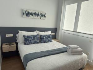 Un dormitorio con una cama con almohadas azules y blancas. en Alojamientos Dima Costa, en Laredo