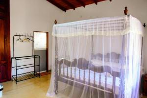 1 dormitorio con 1 cama con cortina blanca en Accoma Villa, en Hikkaduwa