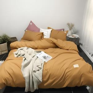 a bed with mustard colored pillows and a blanket at Pin's House in Bao Loc